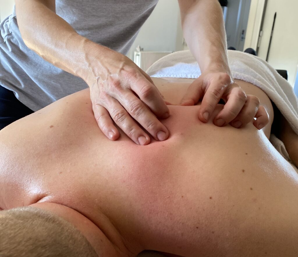 Mand ligger på massagebriks og får massage på ryggen